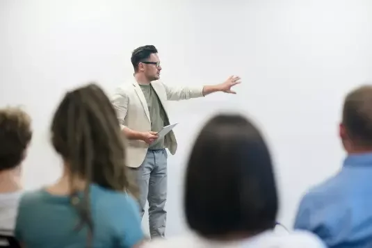 Mann steht an einer Wand und zeigt darauf